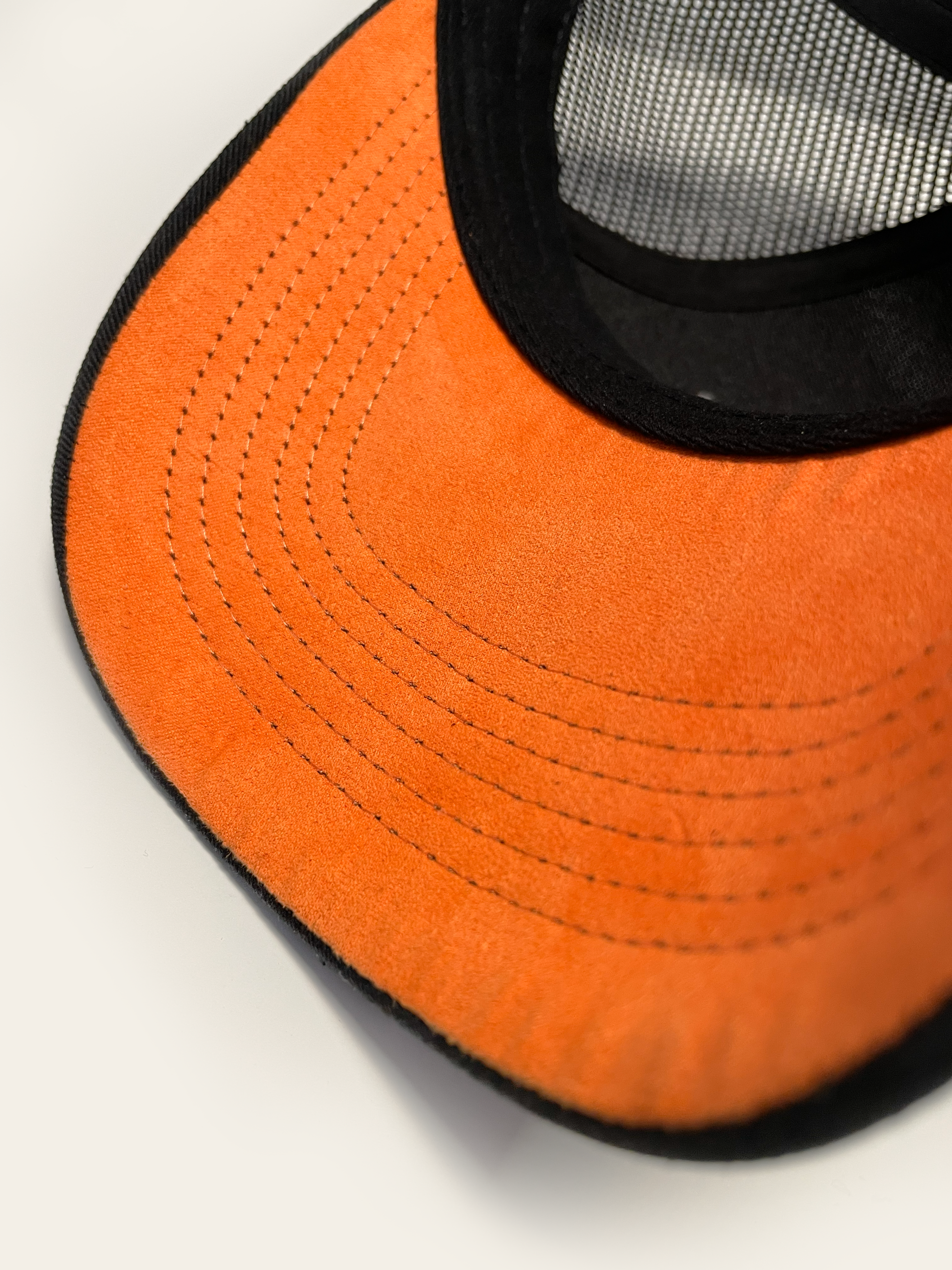 Orange suede underbrim of Front Porch Freestyles Supporter trucker hat showing contrast stitching detail